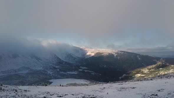 Aerial view of moody snow cowered mountain hills in cold winter weather.