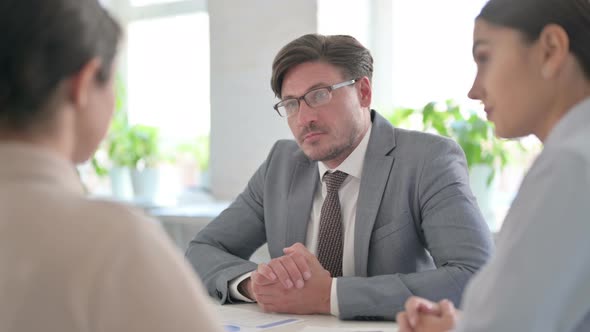 Serious Male and Female Business People having Conversation in office