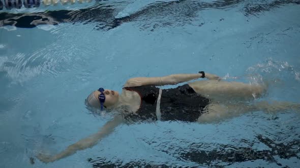 Slow Motion Of Female Amateur Swimmer Practicing Backstroke In Swimming Pool