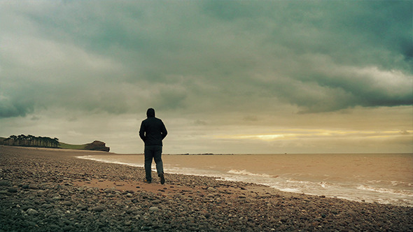 Man Walks Along Sunset Beach alt