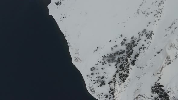 High angle aerial footage of snowy lake shore of Crater Lake, Oregon, USA