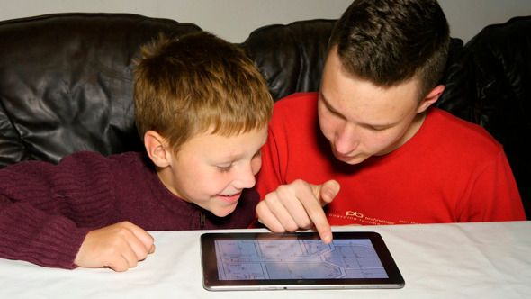 Brothers Using Tablet While Working With Blueprint