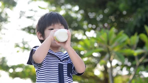 Cute Asian Child Drinking Milk From Glass Bottle