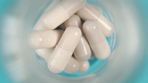 Close-up white medicine capsules in a glass pharmaceutical container 