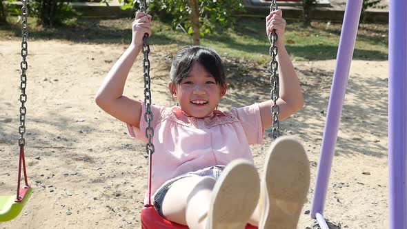 Cute Asian Girl Playing Swing In The Park