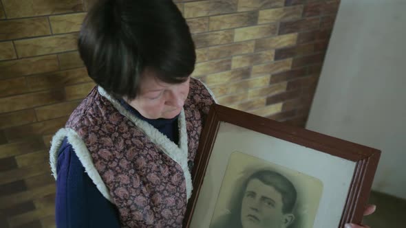 Senior 60s Woman Wipe Old Photo Portrait of an Ancestor