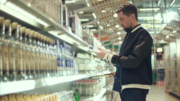 Adult Man is Getting Bottle with a Vodka From Rack of Liquor Store