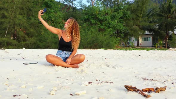 Happy woman with long curly hair taking selfies on the summer vacation.