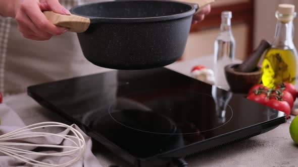 Woman Puts Pot Onto Induction Hob for Boiling