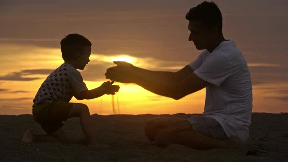 Boy and Dad Playing with Beach Sand at Sunset alt