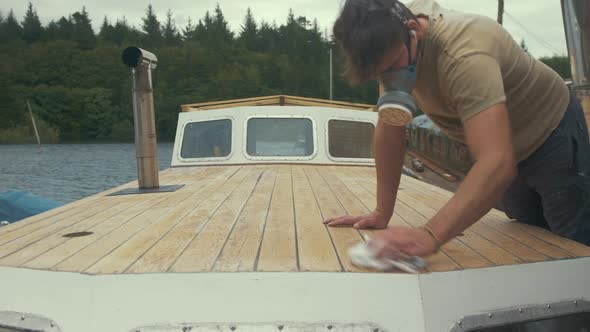 Carpenter wiping sanded roof of wooden boat. Medium wide shot