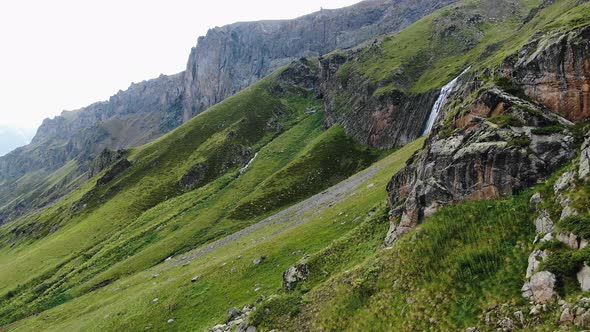 Large Hillside with Rocks Thick Grass on Top and Waterfall