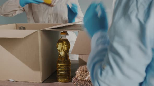 Volunteers Pack Food in Cardboard Boxes Gloves and Medical Masks