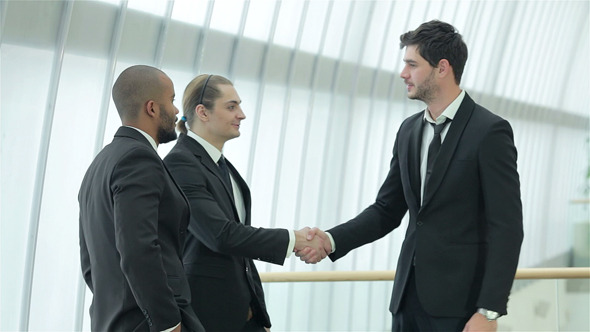 Four Smiling Successful Businessmen Shake Hands
