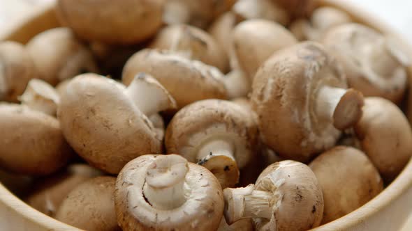 Close Up on Bowl with Fresh Brown Champignons Placed on White Wooden Table. Top View