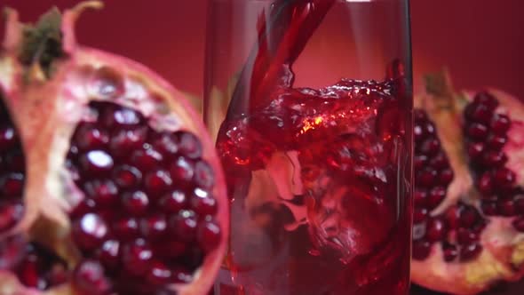 Pomegranate Juice Is Flowing Into a Jug Next To the Ripe Halves of Pomegranates