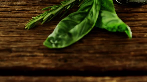 Herbs and bowl of red olives on wooden table