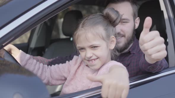 Portrait of Hipster Father and Pretty Daughter Sitting on Driver's Seat and Happily with Smiles