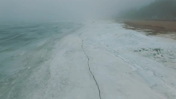 Flying Back Above Frozen Sea Coastline In Misty Cold Winter Day