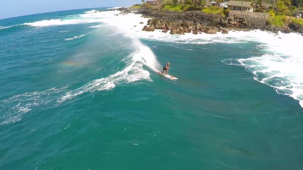 Aerial view of a man sup stand-up paddleboard surfing in Hawaii