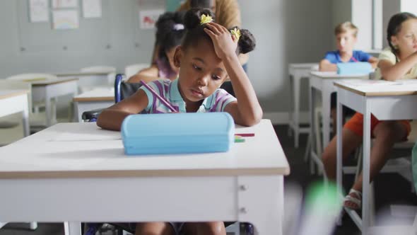 Video of focused african american girl sitting at desk in classroom