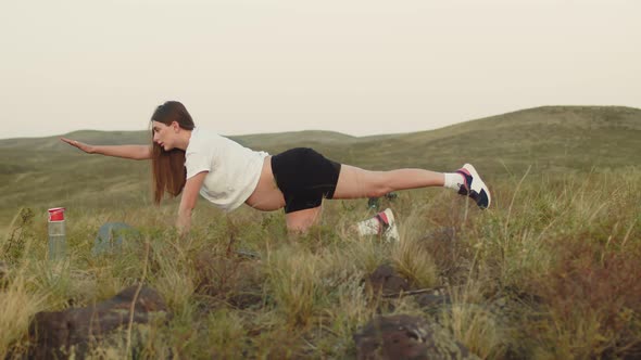 Pregnant Woman Trains Outdoors Performing Yoga Exercises to Strengthen Her Back on Mat There is