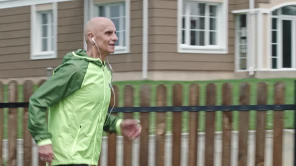 Concentrated Senior Athlete Jogging with Earphones