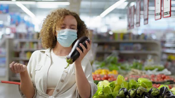 Virus Protection, Woman in a Medical Mask with a Grocery Basket Buys Vegetables in a Grocery