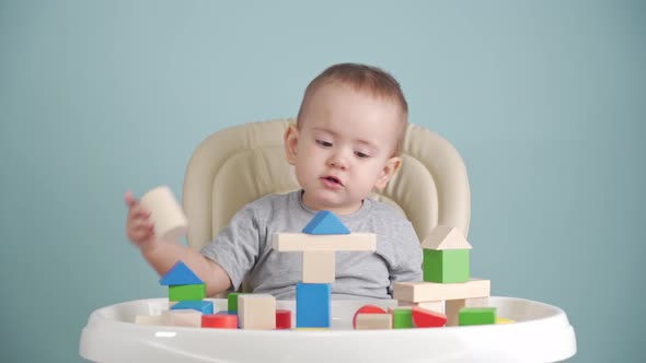 A kid of 15-25 months is learning to build a tower of wooden cubes