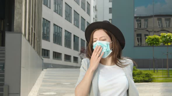 A Woman in a Medical Mask Walking Down the Street and Coughing. A Woman with Signs of Illness Coughs