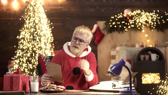 Portrait of Santa Claus Reading Wish List Against Home Christmas Tree