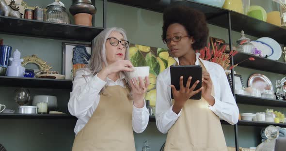 Female Owner of Gift Shop Explaining to Her Young African Amercian Coworker Details of Joint Work