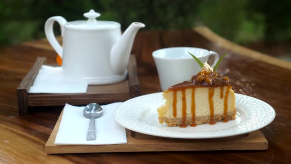 Piece of Delicious Fresh Cake on Wooden Table with White Teapot in Outdoor Cafe