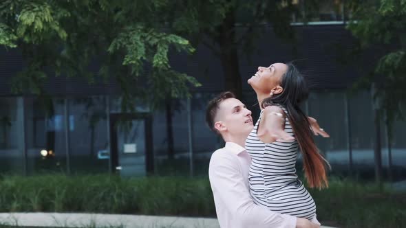 Beautiful Black Girl Raising Hands Up Like Flying Bird While Boyfriend Spinning Her Around Outdoors