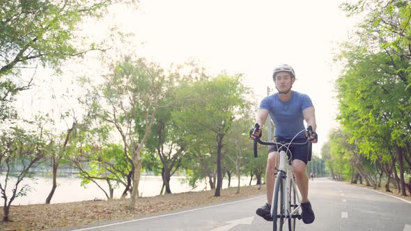 Asian young active sport male in sportswear riding bicycle for health in public park