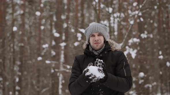 Happy Man in Winter Clothes Sculpts Snowball in Hands and Throws It