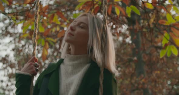 Slow Motion of a Young Woman Relaxing Her Mind on a Swing. Beautiful Lady Reads a Book Under a Big