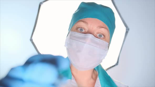 Female surgeon treats a wound to a patient with a cotton swab in the operating room