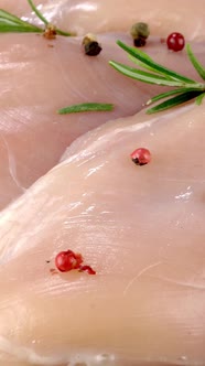 Fresh Raw Chicken Breast Fillets Sprinkled with Peppercorns and Rosemary Rotates Slowly