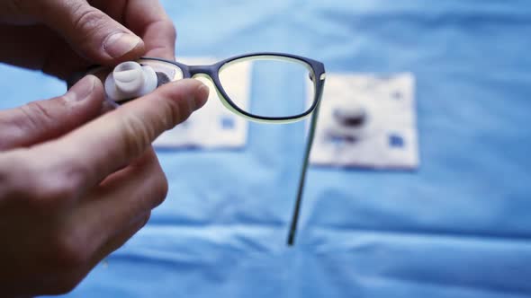 Specialist puts lenses into black frame of eyeglasses.