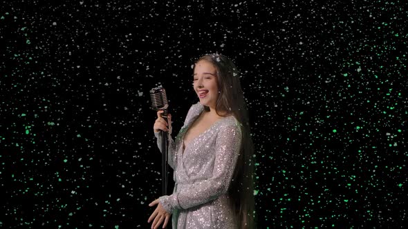 Portrait of a Beautiful Singer with a Vintage Microphone Against the Background of Falling Snow