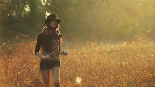 Girl in the Hat Walks in the Evening on a Meadow