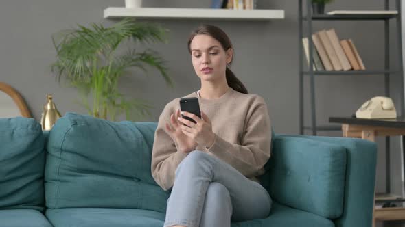 Woman Using Smartphone on Sofa