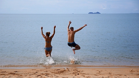Couple on Vacation Jumping in the Sea