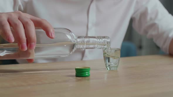 Close Up Of Man'S Hands Pouring Vodka In A Shot Glass Before Drinking At Home