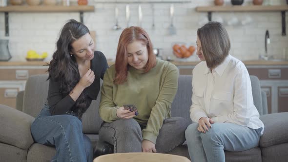 Three Young Carefree Women Using Social Media on Smartphone and Chatting