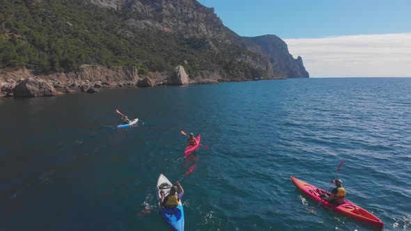 Aerial Tourists on Kayaks Sail on Sea Against Rocky Coast