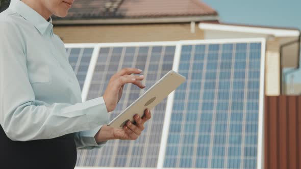 Woman with Tablet Standing Before Solar Panels