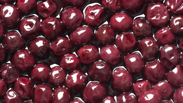 Cherries in alcohol in their own juice in a plate, close up, top view, rotates