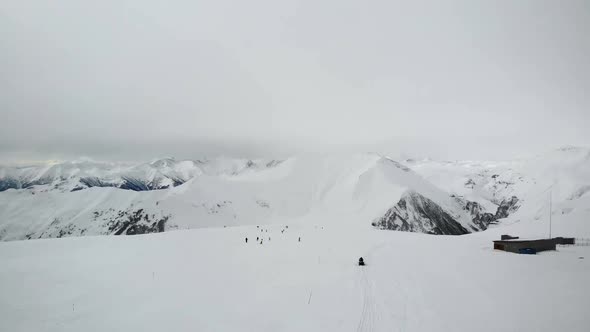 Tourists Riding From Snowy Hill in Mountains.